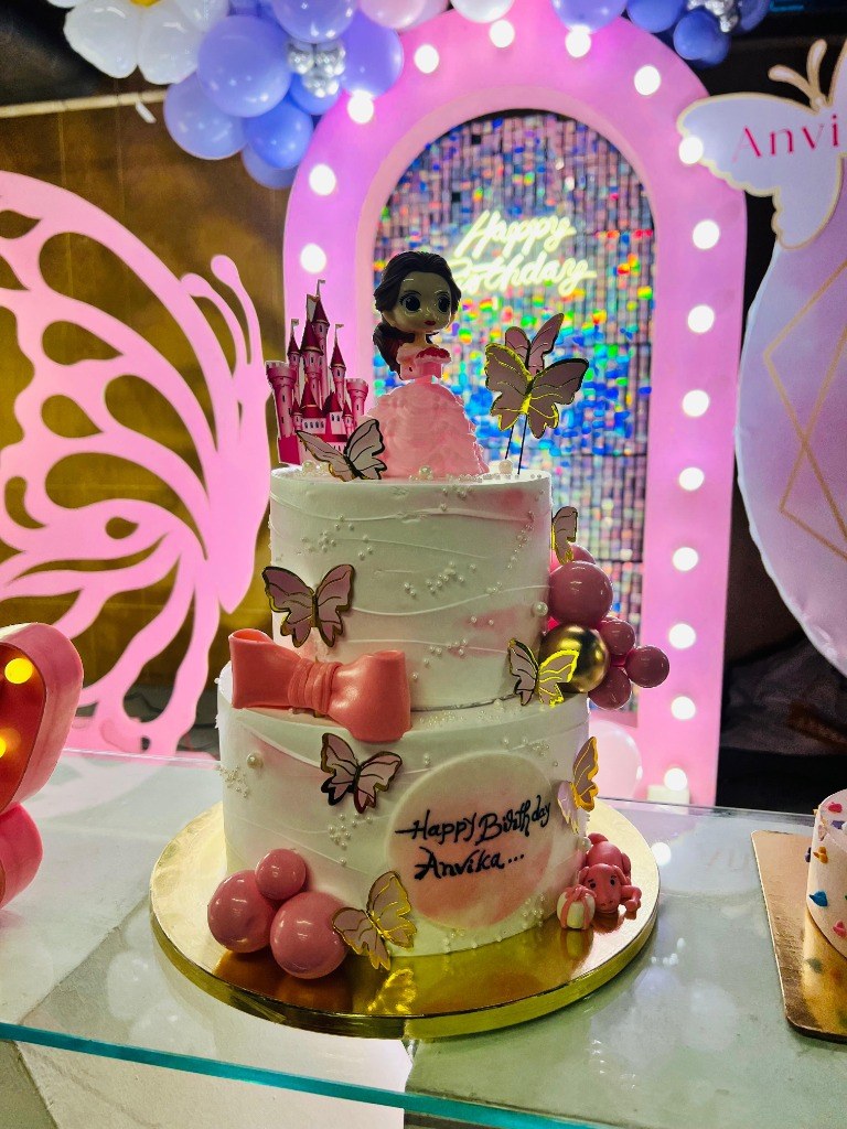 Custom two-tier fairy birthday cake with castle topper and pink fondant bow